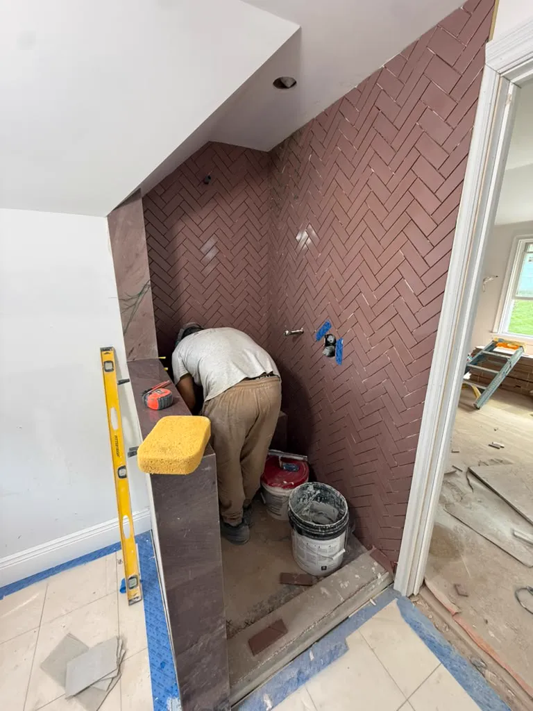 Tile setter laying herringbone tile in a shower
