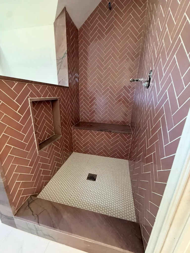 Herringbone tile shower with recessed niche and bench