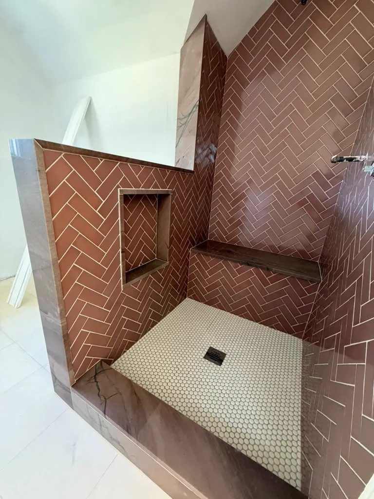 Finished herringbone shower with niche, bench and stone half wall