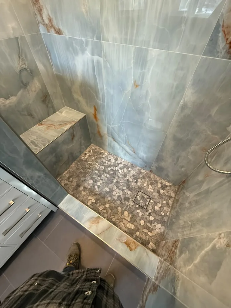 Shower with stone slab walls and pebble floor