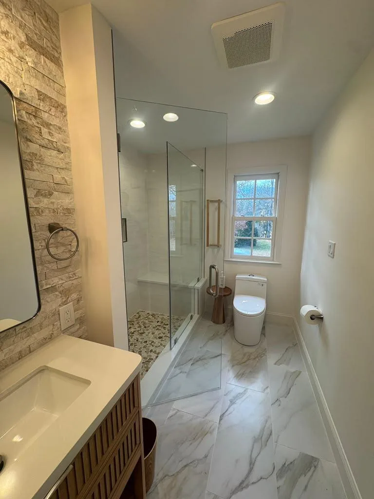 Corner frameless glass enclosure beside a stone accent wall