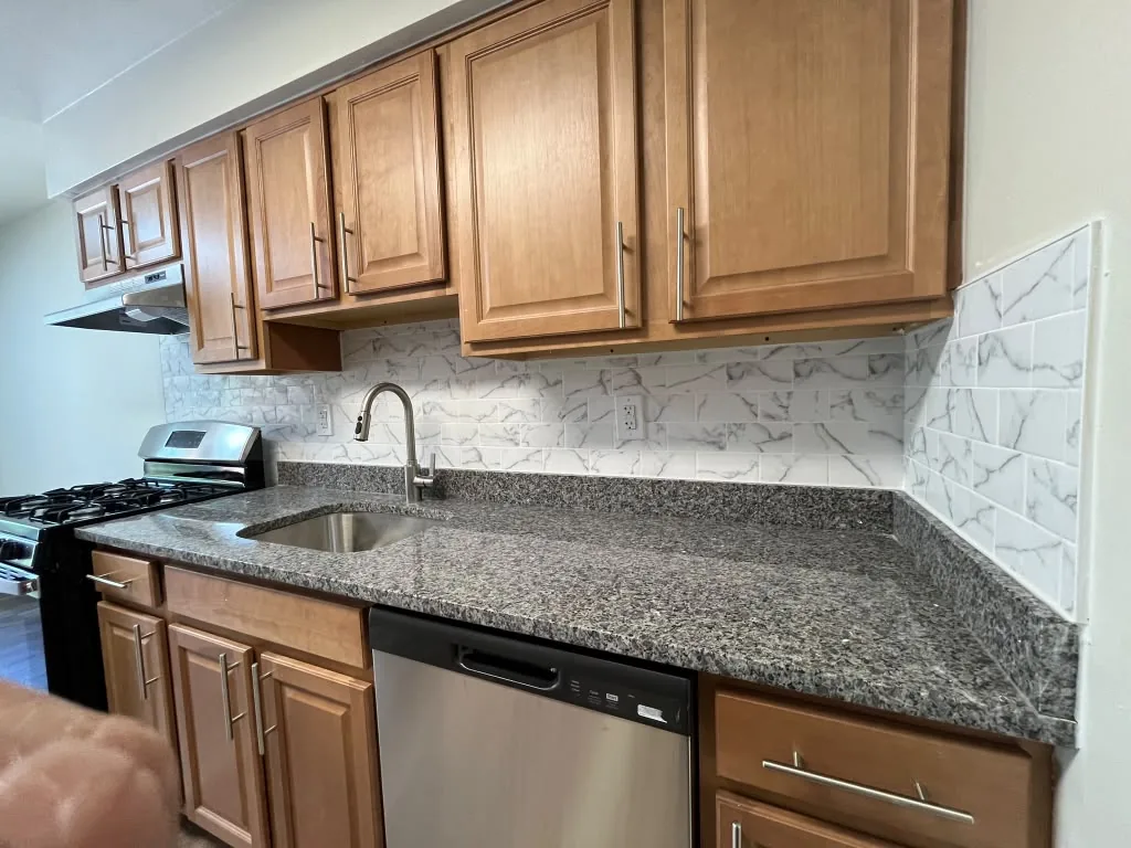 Close view of granite counter, sink and stone backsplash