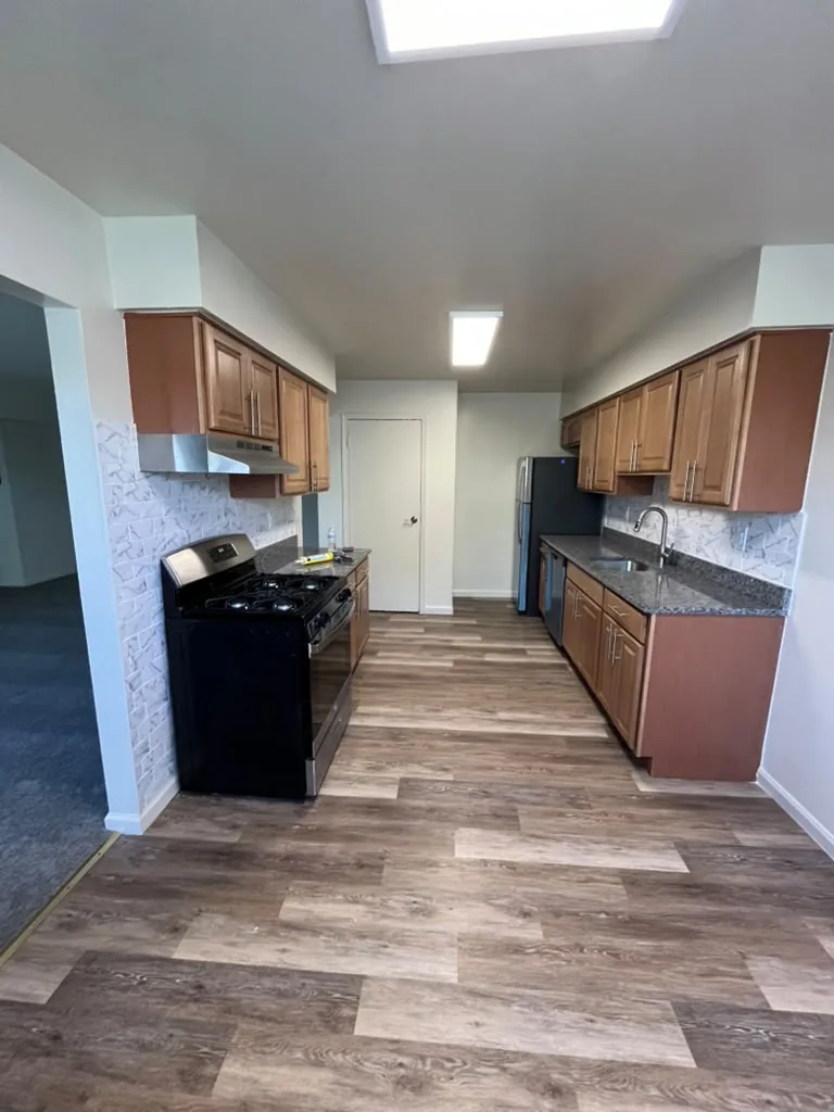 Wide view of a kitchen with wood cabinets and vinyl plank flooring