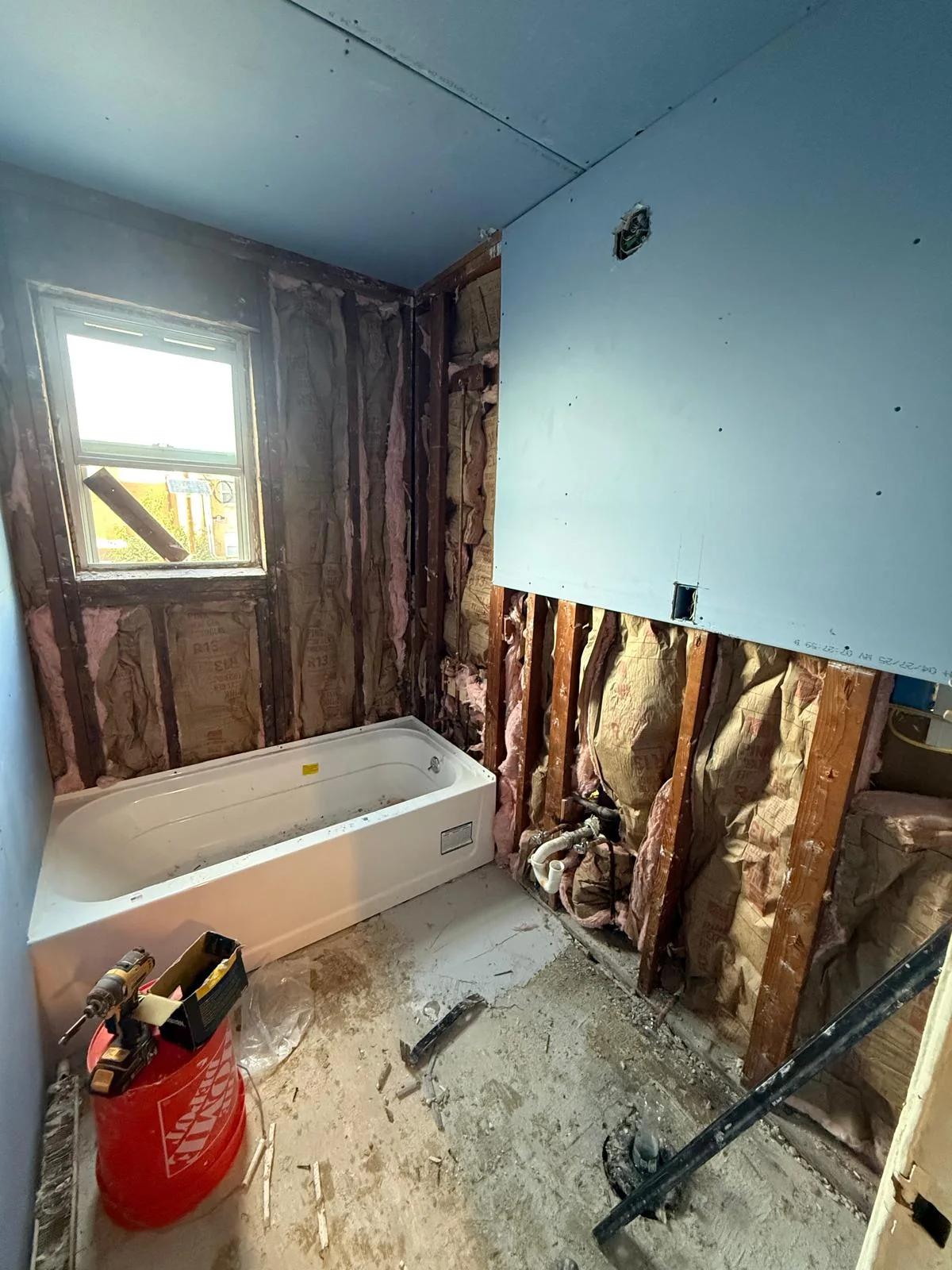 Bathroom stripped to the studs during demolition, framing and insulation exposed