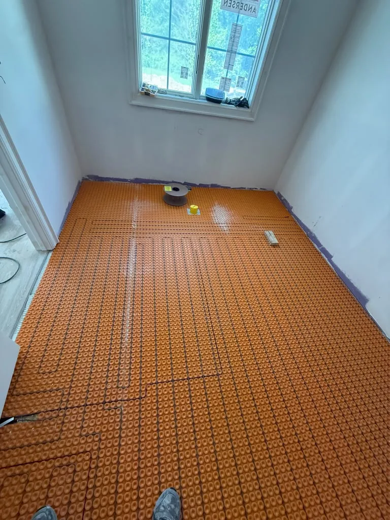 Uncoupling membrane installed across a bathroom floor before tile