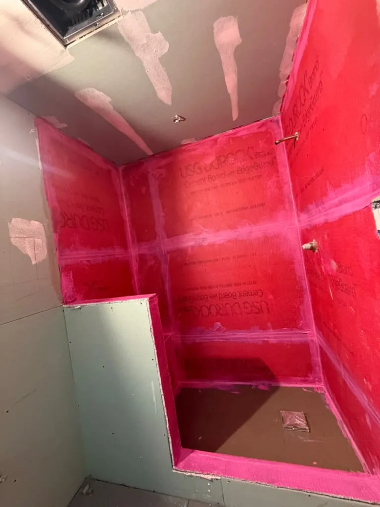 Shower walls coated in red waterproofing membrane before tiling